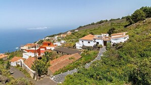 A coastal village with white buildings and red roofs, surrounded by greenery and overlooking the sea.