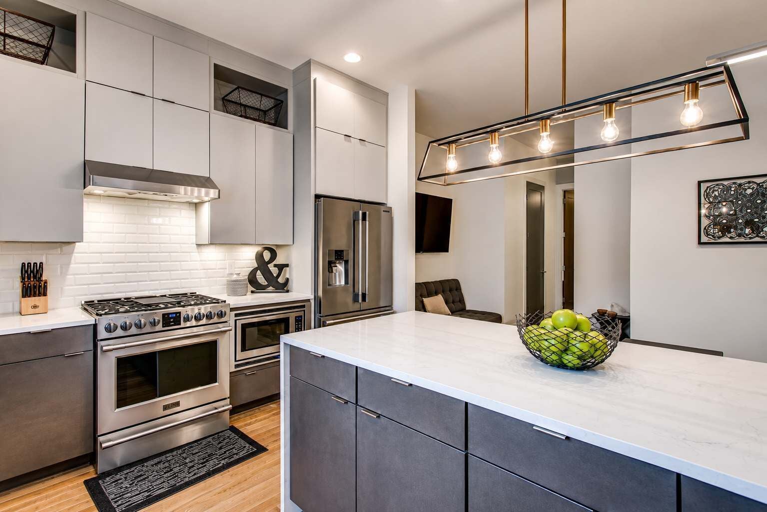 A modern kitchen with stainless steel appliances, a central island, and a pendant light fixture.