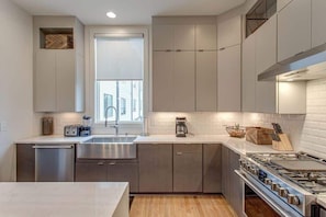 A modern kitchen with stainless steel appliances, a dishwasher, and a window providing natural light.