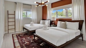 A hotel room with two beds, a wooden ladder, a patterned rug, and a view of greenery outside. - Terracotta Suite 2BD/2BA Miami Beach Lincoln Suite (Miami Beach)