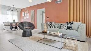 A modern living room with a grey sofa, wicker chairs, a coffee table, and a wooden accent wall. - Terracotta Suite 2BD/2BA Miami Beach Lincoln Suite (Miami Beach)