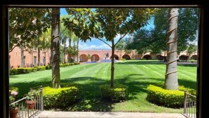 A courtyard with a stone staircase leading up, surrounded by well-manicured lawns and trees. - El Diezmo Hotel (San José Iturbide)