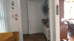 A hallway with a closed door, a potted plant, and a small table with items on it. - GRANDMA'S COTTAGE  (Monticello)