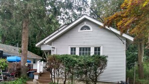 A single-story house with a front porch, a small garden, and a wooden fence. - GRANDMA'S COTTAGE  (Monticello)