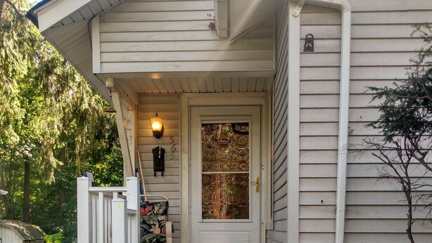 A house with a front porch, a front door with a glass panel, and a small step leading up to the door. - GRANDMA'S COTTAGE  (Monticello)