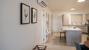 Una cocina moderna con una isla central, un comedor con mesa y sillas, y obras de arte enmarcadas en la pared.
