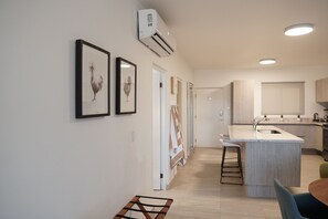 A modern kitchen with a central island, a dining area with a table and chairs, and framed artwork on the wall.