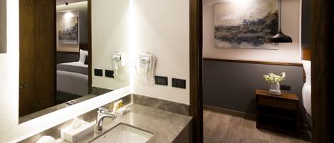 A modern bathroom with a large mirror, a sink, and a hairdryer mounted on the wall.