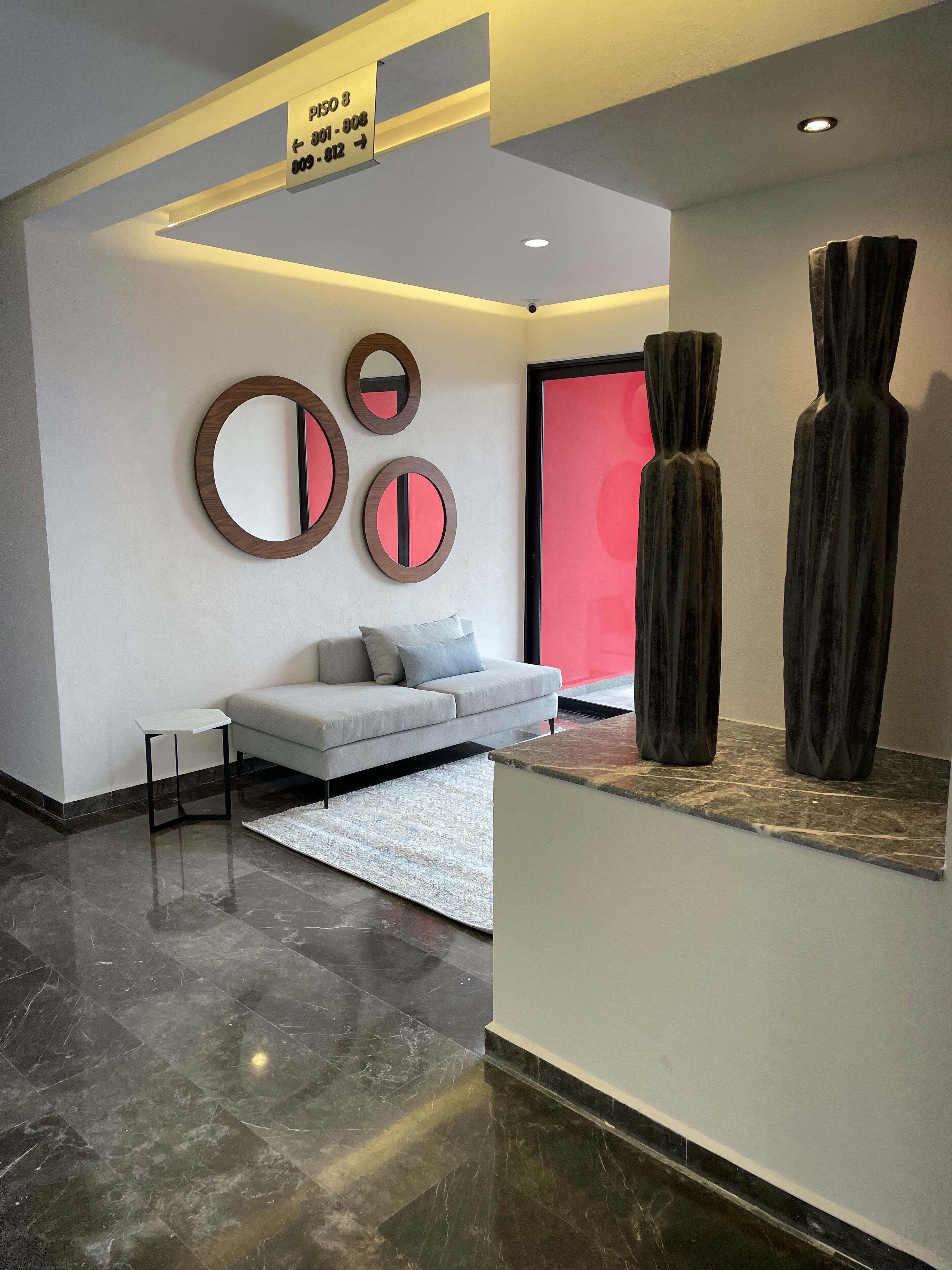 A modern interior with a grey sofa, a white rug, and abstract wall art.
