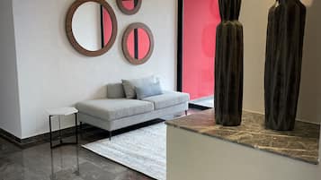 A modern interior with a grey sofa, a white rug, and abstract wall art.