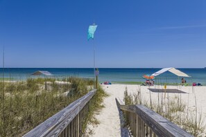 A beach pathway leading to the shore with beach umbrellas and a flag. - Gulf of America View, Hot Tub, Steps to Sand! (Gulf Shores)
