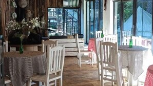 Un restaurante con vigas de madera en el techo, mesas redondas con manteles a cuadros y sillas.