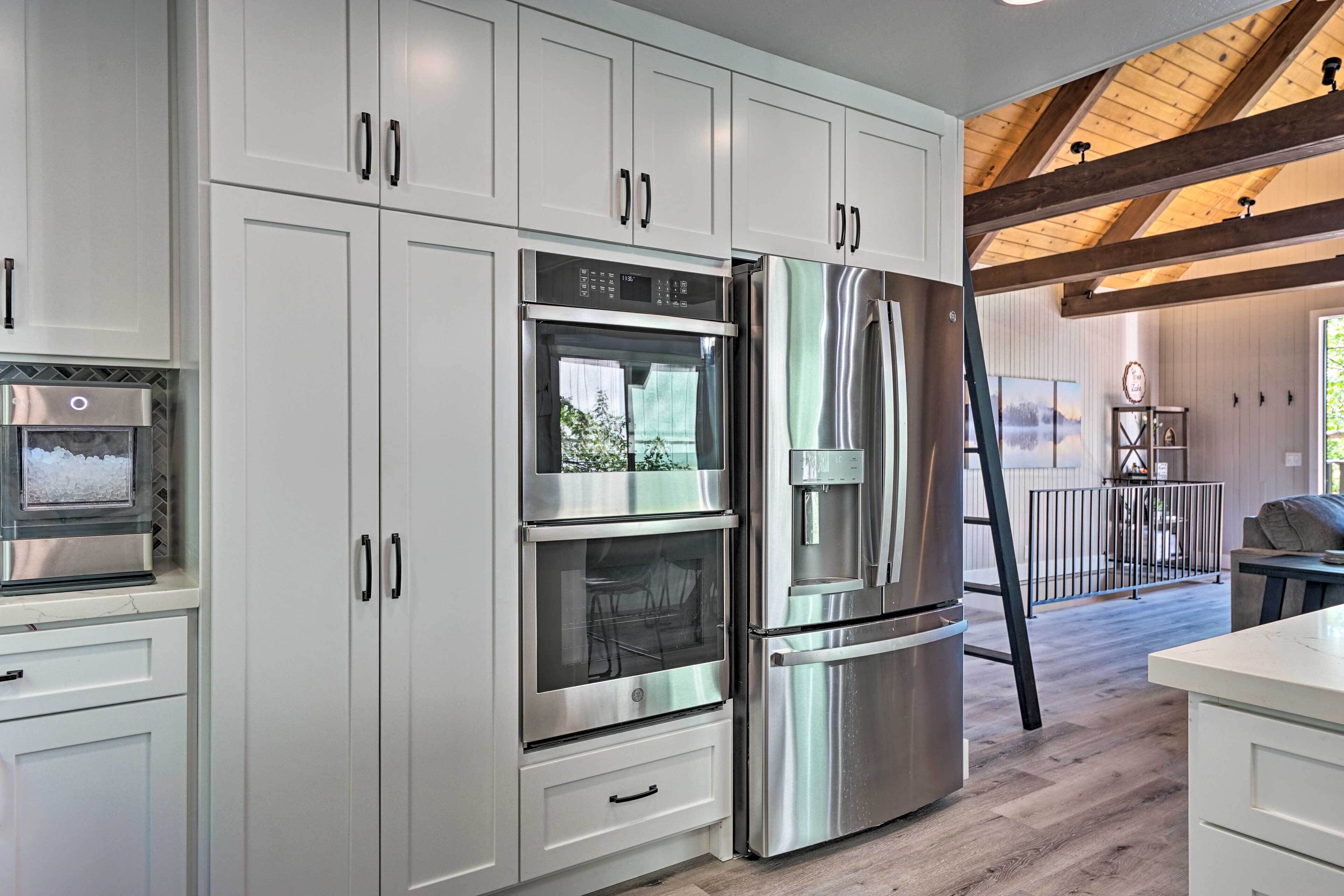 Een moderne keuken met roestvrijstalen apparatuur, witte kasten en een houten plafond.