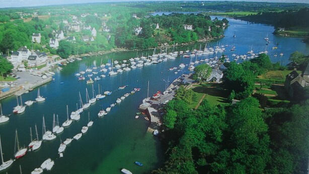 An aerial view of a marina with numerous boats docked, surrounded by lush greenery and residential buildings. - Lovely house with private parking/covered terrace close to beaches and amenities. (Douarnenez)