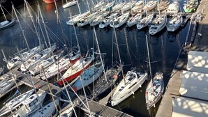 A marina with numerous boats docked, a red boat in the foreground, and buildings in the background. - Lovely house with private parking/covered terrace close to beaches and amenities. (Douarnenez)