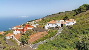 A coastal village with white buildings and red roofs, surrounded by greenery and overlooking the sea.