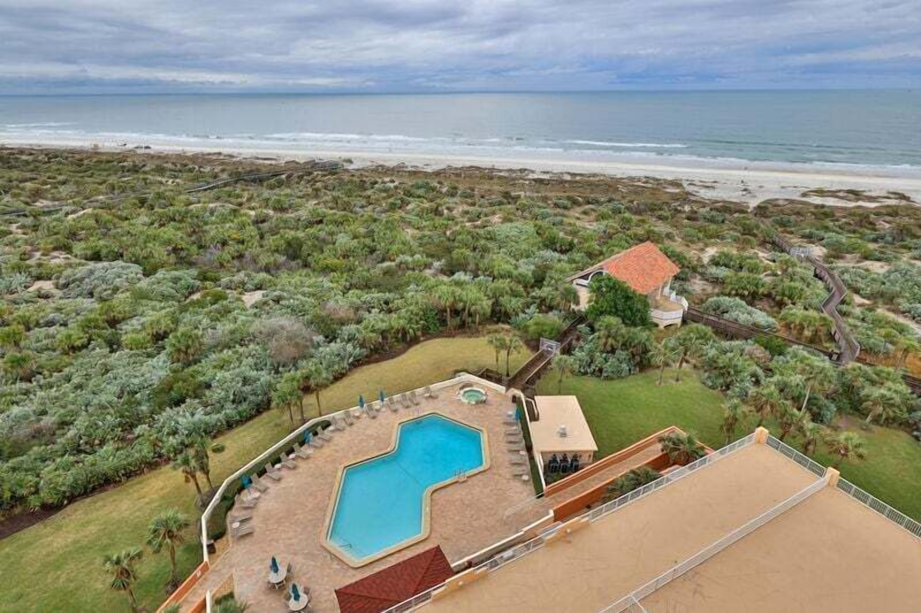 A resort with a swimming pool, beach view, and landscaped garden.