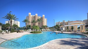 A swimming pool with a tiled deck, surrounded by palm trees and lounge chairs. - Dazzling Dune Delight | Inlet #902 (New Smyrna Beach)