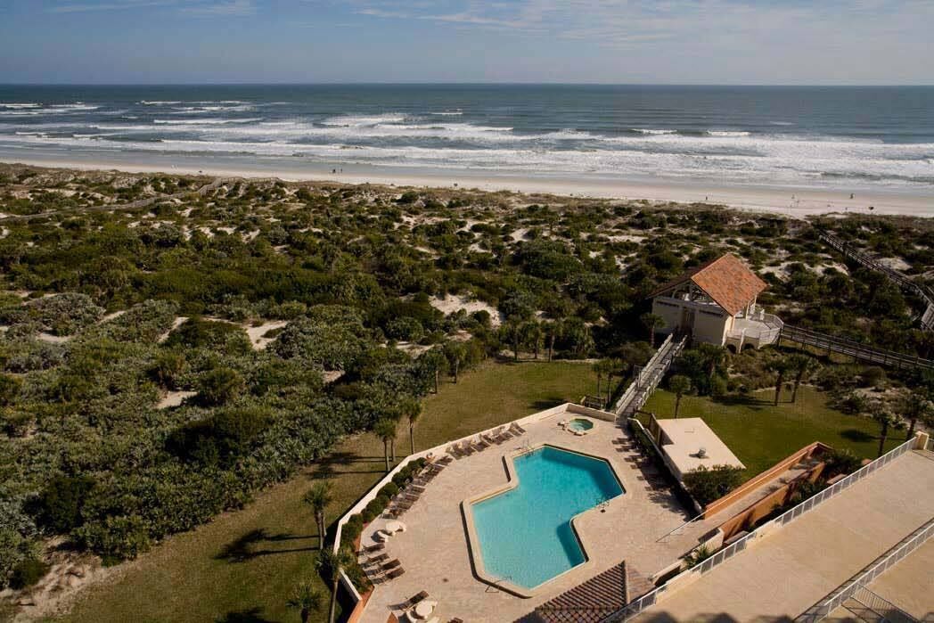 A resort with a swimming pool, a beach view, and a slide.