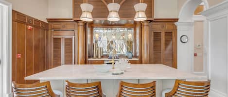 A spacious kitchen with a large island, wooden cabinetry, and modern pendant lighting.