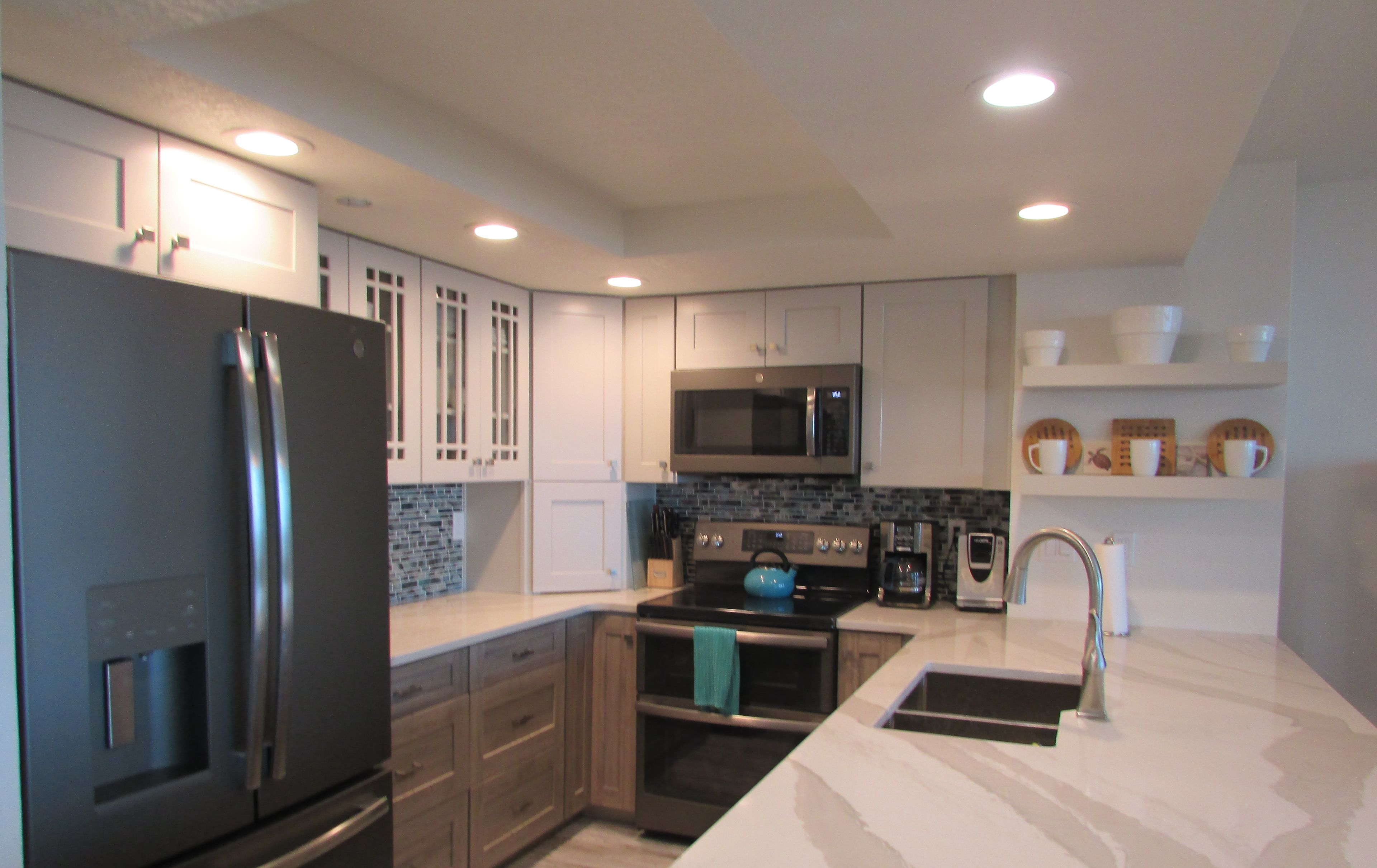 A modern kitchen with a stainless steel refrigerator, a microwave, a stove, and a sink.