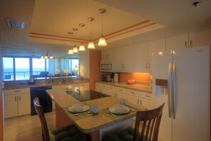 A modern kitchen with a central island, white cabinets, and a view to the outside.
