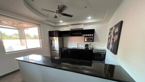 Una cucina moderna con una grande isola, elettrodomestici integrati e una ventola a soffitto.