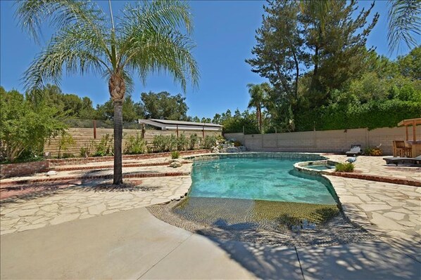 Relax by the pool surrounded by lush greenery and lounge chairs.