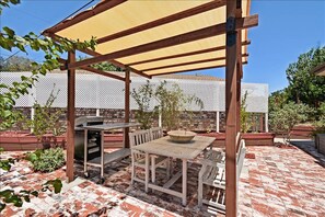 Relax outdoors with a barbecue grill, fire pit, and comfortable seating under a shaded pergola.