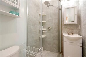 A bathroom with a glass-enclosed shower, a white sink, and a mirror above the sink. - Furnished Cottage, Los Angeles California (Los Angeles)
