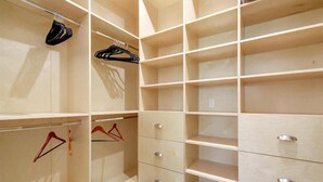 A walk-in closet with open shelving and drawers, featuring metal hangers and a wooden floor. - Furnished Cottage, Los Angeles California (Los Angeles)