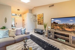 A living room with a sofa, a coffee table, a TV, and a painting on the wall. - Luxury 3-Bedroom Home with Pool Near Stadium-Perfect for Game Weekends (Glendale)