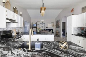 A modern kitchen with a marble countertop, stainless steel appliances, and white cabinetry. - Luxury 3-Bedroom Home with Pool Near Stadium-Perfect for Game Weekends (Glendale)
