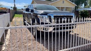 A black pickup truck parked in front of a house with a white picket fence.