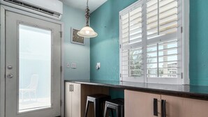 A kitchen with teal walls, a white door, and a window with blinds.