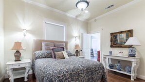 A bedroom with a large bed, two bedside tables, a nightstand, a dresser, a console table with decorative items, and a door leading to another room. - It's Our Location...Easy to get to many Dallas Destinations (Dallas)