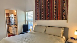 A bedroom with a bed, bedside table, and a window with blinds.