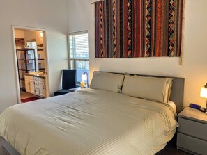 A bedroom with a bed, bedside table, and a window with blinds.