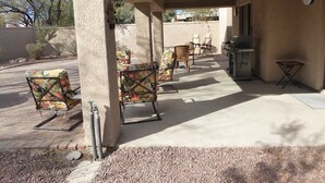 An outdoor patio area with a covered seating area, a grill, and a small table.