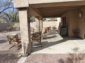 An outdoor patio area with a covered seating area, a grill, and a small table.