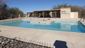 A rectangular swimming pool with a shaded area and a covered seating area.