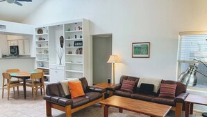 A living room with a sofa set, a coffee table, and a dining area with chairs and a table.