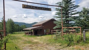 A rustic wooden building labeled "Little Moose Lodge" with a covered porch and a fenced entrance.