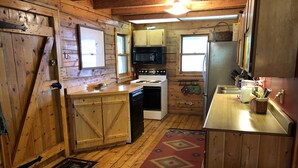 Cocina compacta con paredes de madera, estufa, microondas y refrigerador.