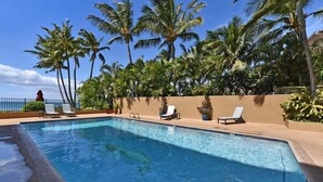 A swimming pool with lounge chairs and palm trees.
