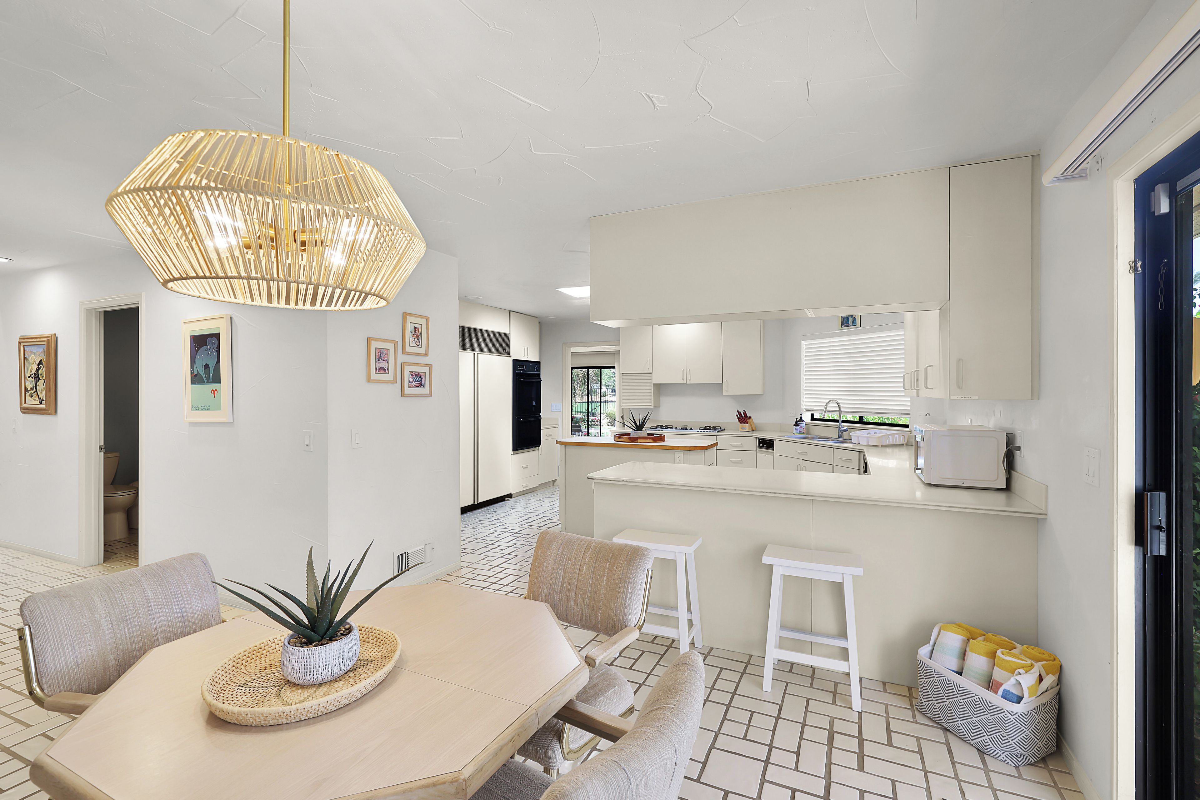 Une cuisine moderne avec des meubles blancs, un îlot central et un luminaire suspendu.