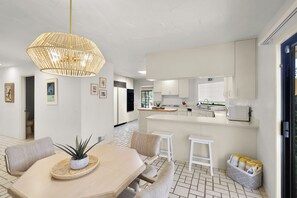 Et moderne køkken med hvide skabe, en central ø og en hængende lampe.