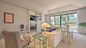 Una sala de estar con una mesa de centro de vidrio, un sofá, un televisor y una chimenea.