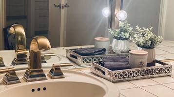 Un tocador de baño con un espejo grande, luces de tocador y un lavamanos.