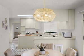 Et moderne køkken med hvide skabe, en central ø og en hængende lampe.